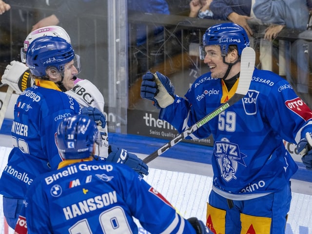 Eishockeyspieler in blauen Trikots jubeln auf dem Eis.