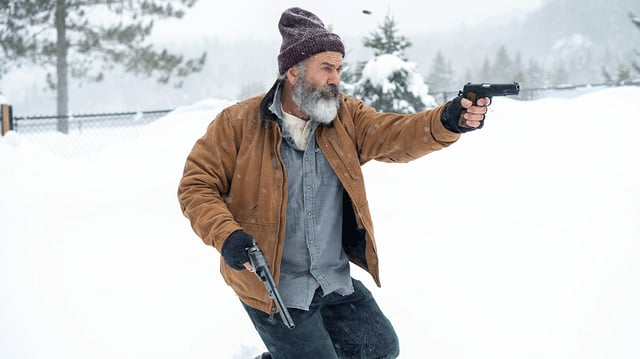 A man with a white beard and a cap runs through a snowy landscape and shoots two pistols.