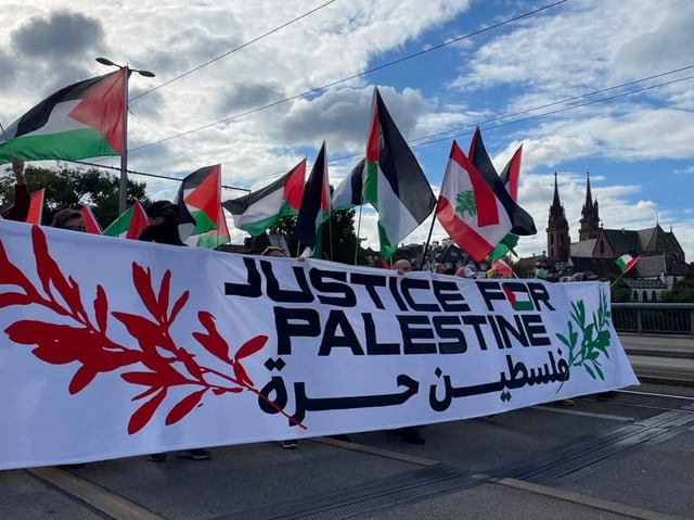 Demonstration mit Palästina-Flaggen und Banner 'Justice for Palestine'.