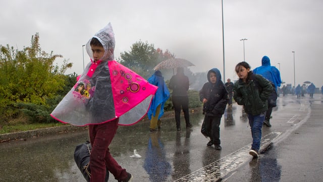 Kinder laufen im strömenden Regen auf einer Strasse,