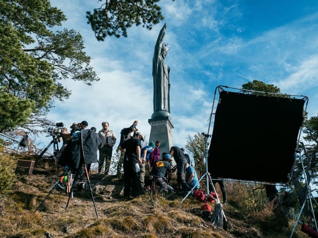 Die Filmcrew steht um eine Statue versammelt.