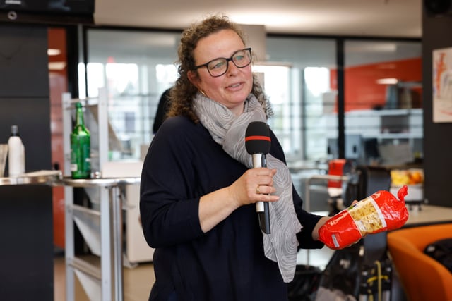 Frau mit Mikrofon und einer Packung Nudeln in der Hand