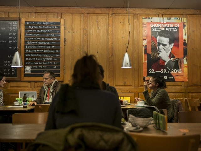 Menschen sitzen in einem Restaurant mit Holzwand