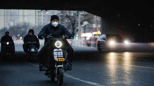 Das Bild zeigt einen Mann auf einem Scooter mit Maske.