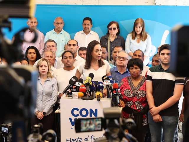 Machado spricht an einer Pressekonferenz, und ist umgarnt von Menschen in ihrem Rücken, die ihr zuhören.