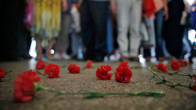 Rote Blumen liegen als Zeichen der Trauer auf dem Boden. 