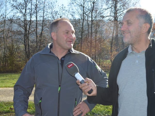 Zwei Männer reden miteinander, einer von ihnen hat ein SRF-Mikrofon in der Hand