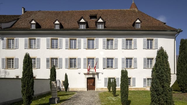 Weisse historische Villa mit Bäumen und Flagge.