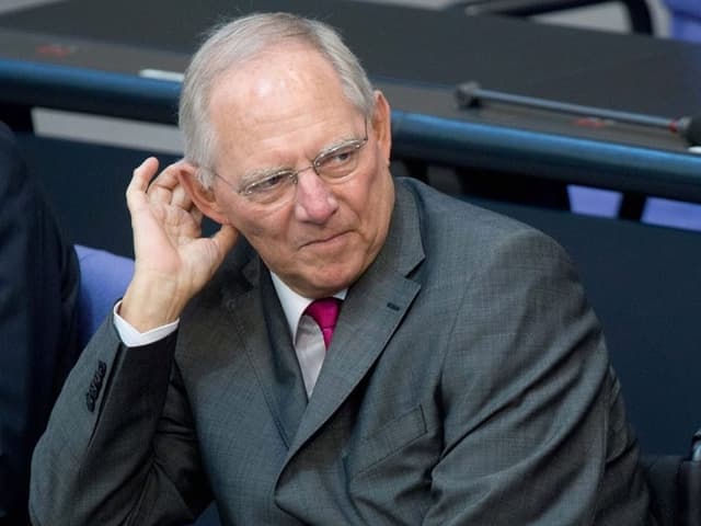 Wolfgang Schäuble sitzt seinen rechten Arm aufstützend an einem Tisch im deutschen Bundestag.