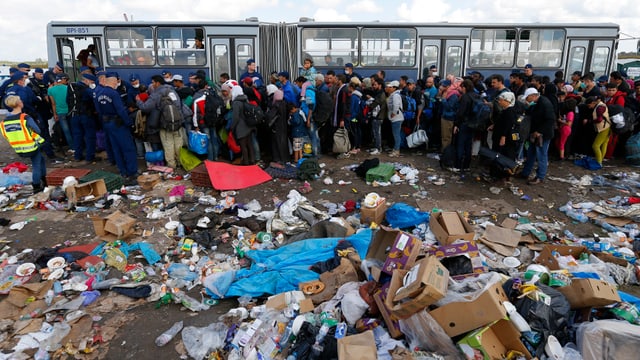 Menschen inmitten von Müll vor einem Bus