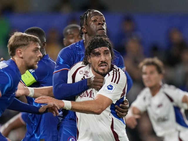 Fussballspieler in blauen und weissen Trikots kämpfen um den Ball.