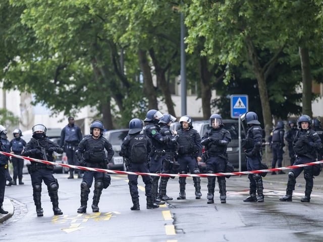 Viele Polizistonnen udn Polizisten hinter einem Absperrband.