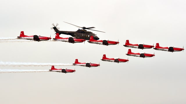 Flugzeuge des PC-7-Teams und ein Super Puma nebeneinander in der Luft