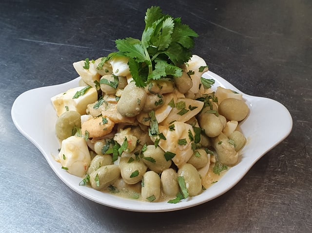 Salat mit grossen weissen Bohnen auf weissem Teller angerichtet.