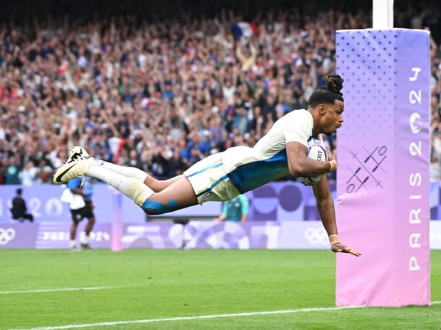 Rugbyspieler taucht mit dem Ball am Zielpfosten von Paris 2024 ins Tor.