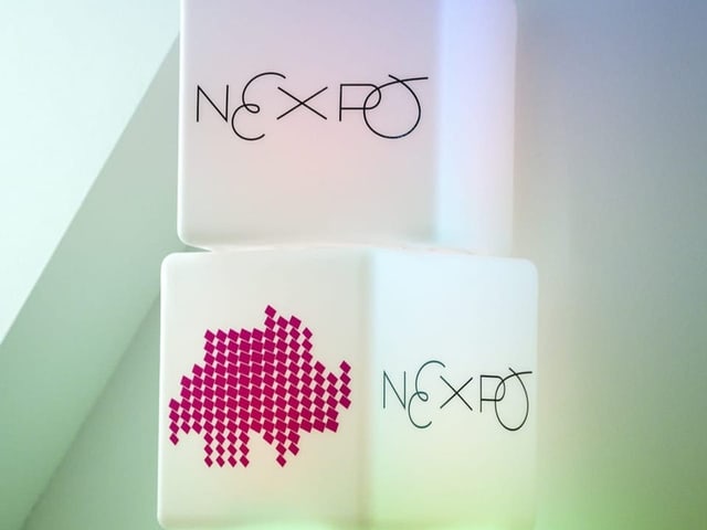 Leuchtendes NEXPO-Logo, darunter rote Karte der Schweiz.