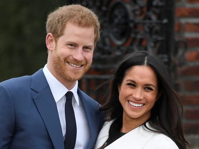 Harry und Meghan posieren lächelnd.