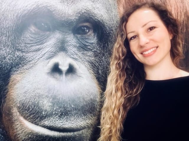 Eine Frau mit langen Haaren und ein Affe, beide lächelnd