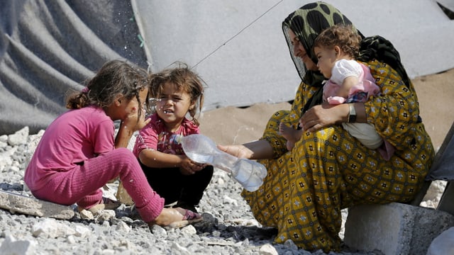 Ein syrische Frau mit ihren drei Kindern in einem Flüchtlingslager. 