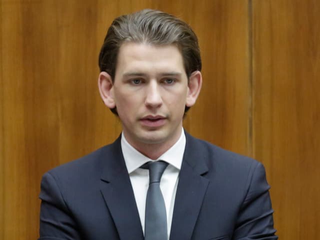 Kurz in einem Brustbild vor brauner Holzwand