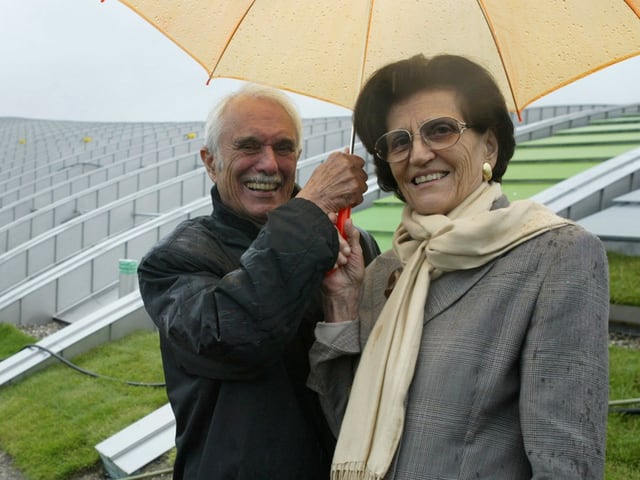 Ein Mann hält einen Regenschirm über eine Frau.