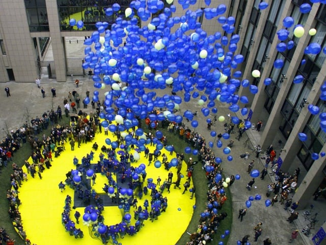 Blaue Ballone steigen in einem grossen Innenhof auf.