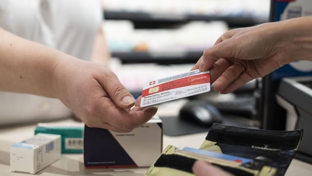 Eine Person übergibt in der Apotheke die Krankenkassenkarte.