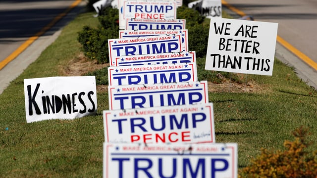 Trump/Pence-Schilder auf einer Grünfläche, Schilder «Kindness» und «We are better than this» daneben.