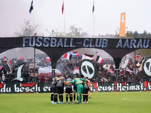 Fussballspieler-Umarmung vor jubelnden Fans im Stadion.