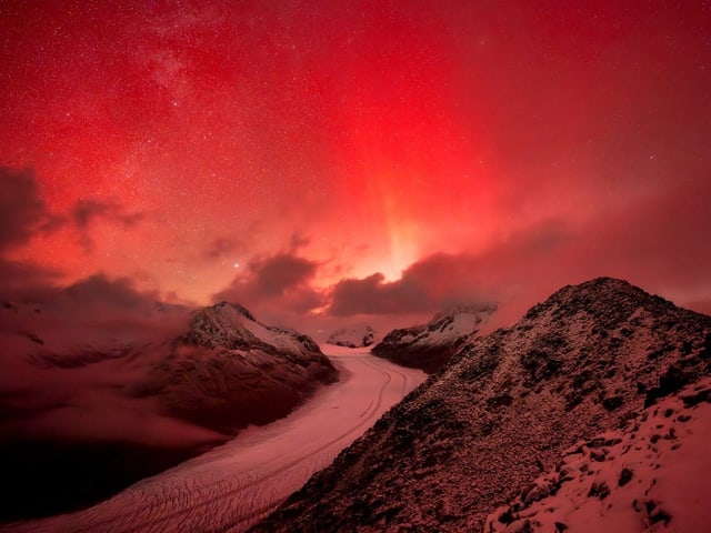 Roter Himmel über verschneiten Bergen bei Nacht.