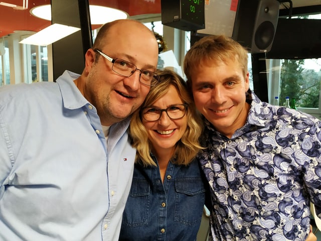 Michael Brunner, Ladina Spiess und Reto Scherrer posieren für ein Gruppenbild im Studio.