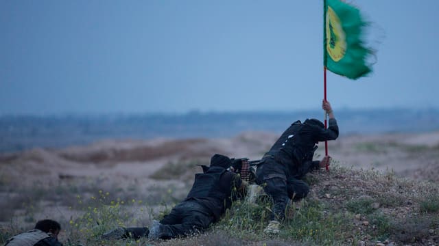 Ein schiitischer Miliziönar versenkt eine Flagge im erkämpften Territorium bei Tikrit