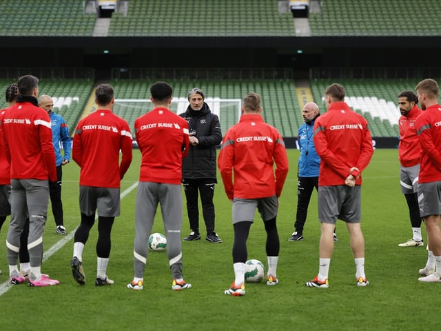 Fussballtrainer, der einen Kreis von Spielern auf dem Spielfeld anleitet.