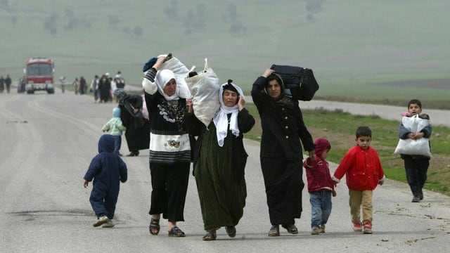 Eine Flüchtlingsfamilie mit Gepäck auf der Landstrasse.