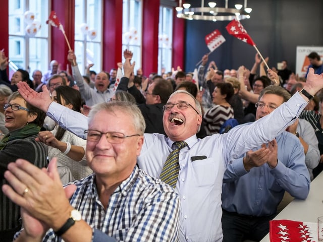 Jubelnde Menschen mit Walliser Fahnen.