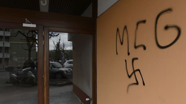 Gebäude mit Graffiti und Hakenkreuz-Symbol an der Wand.