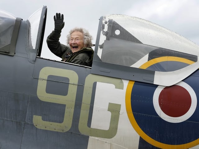 Alte Frau winkt aus dem Cockpit.