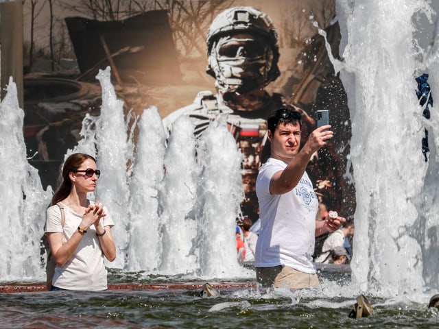 Mann und Frau in einem Brunnen. Wasserfontänen umranden sie.