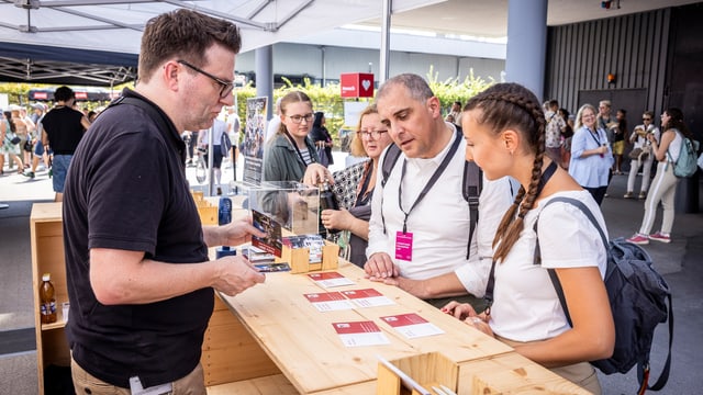 Ein SRF-Mitarbeiter spricht mit Besuchenden am «Hallo SRF!»-Stand.