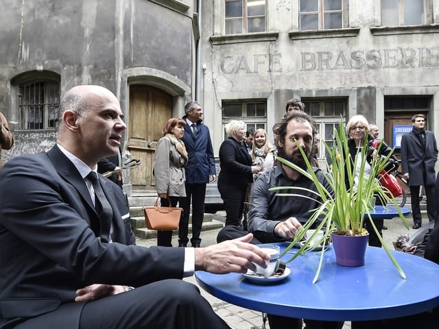 Alain Berset auf einem Platz an einem Bistro-Tisch sitzend.