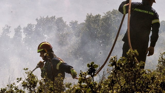 Zwei griechische Feuerwehrmänner mit Löschschlauch.