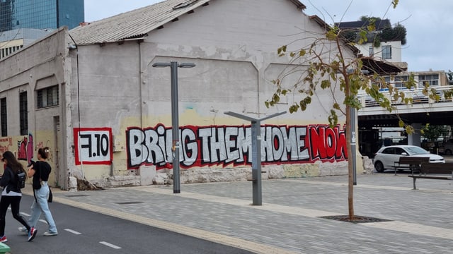 Graffiti an einer Hauswand, mit dem Schriftzug: Bring them home now