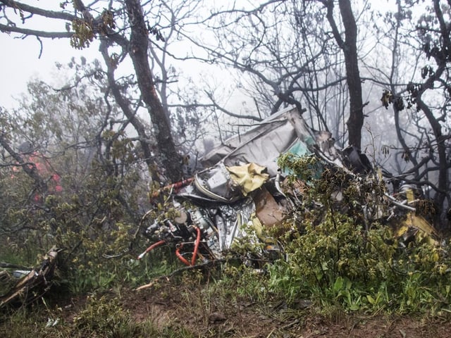 Flugzeugwrack im bewaldeten Gebiet mit Nebel im Hintergrund.