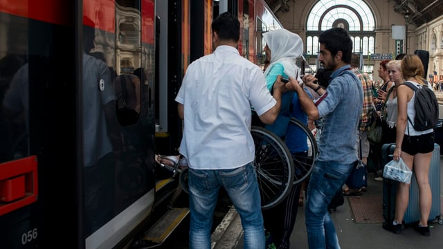 Ein Mann hilft einer Frau im Rollstuhl in den Zug