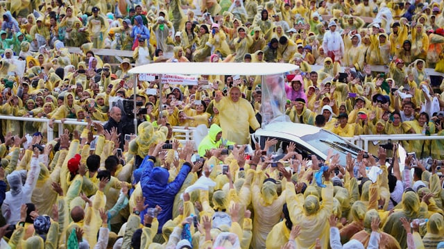 Papst im Regenschutz im Papamobil.