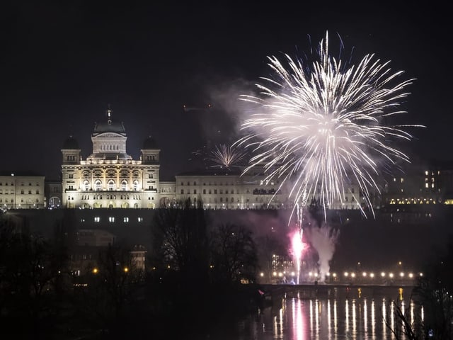 Das Bundeshaus in Bern. Von einer Brücke wird ein Feuerwerk gezündet.