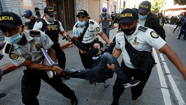 Police officers carry a protester.