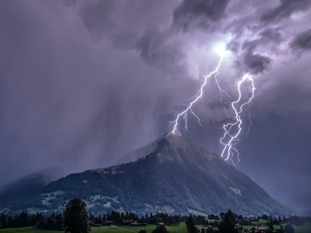 Blitzeeinschläge in der Nacht an einem Berg.