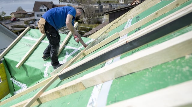 Arbeiter auf einem Dach bei der Montage von Brettern