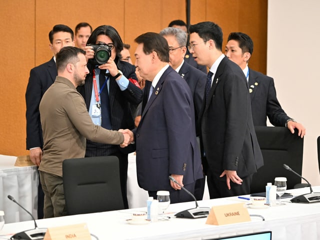 Yoon Suk Yeol und Selenski schütteln sich die Hände, umringt von Journalisten.